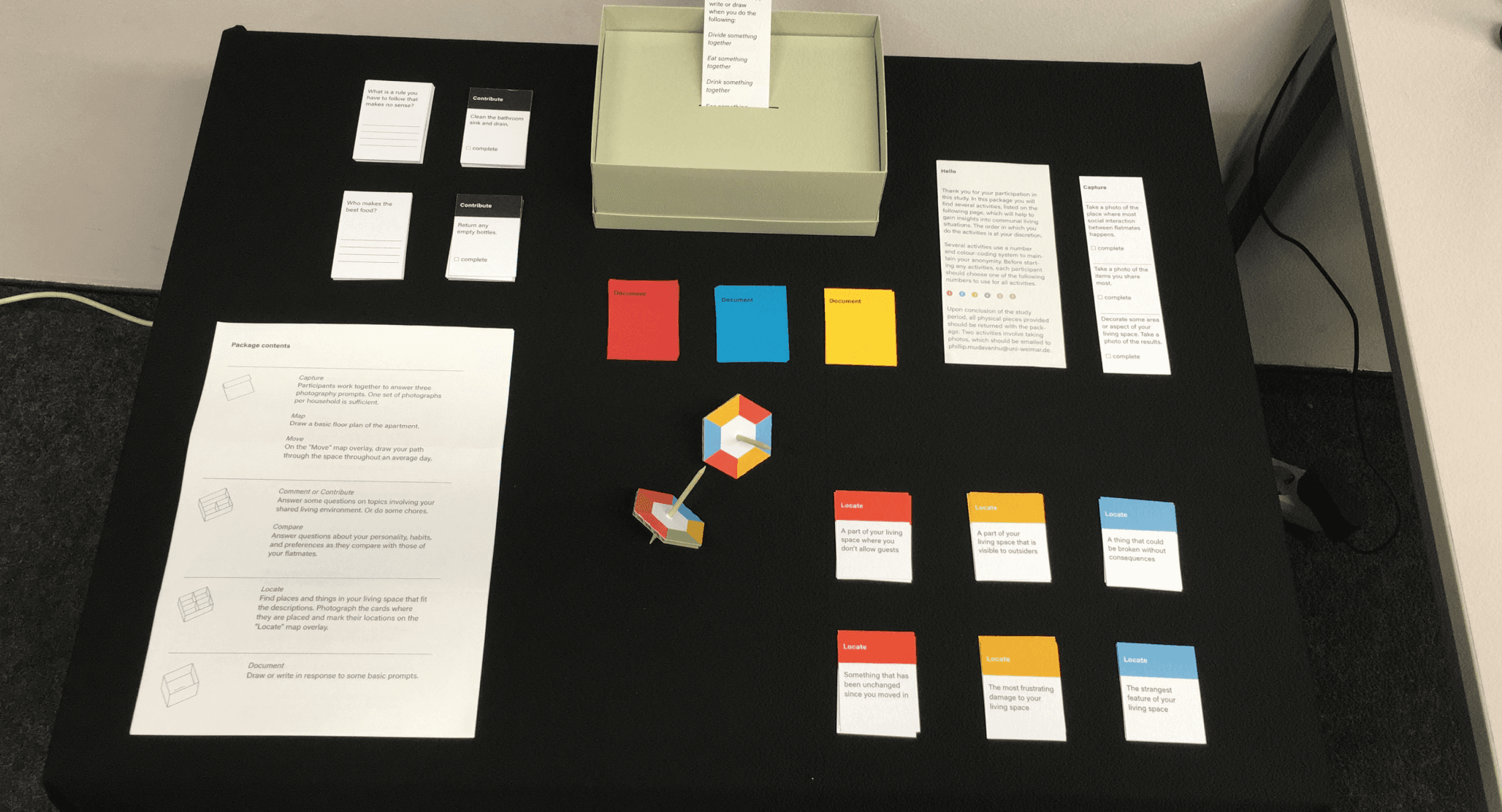 The cultural probe cards, prompts and spinning wheel laid out on a black table