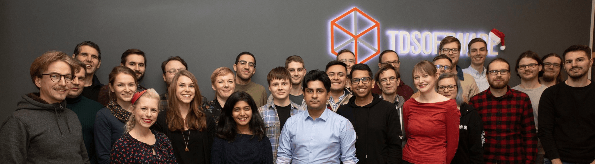The TDSoftware team in front of the company logo